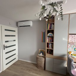 Klimalandia Kamil Zwirowicz - Biały klimatyzator ścienny w pokoju dziecięcym z regałem na książki i biurkiem, widok z niskiego kąta.