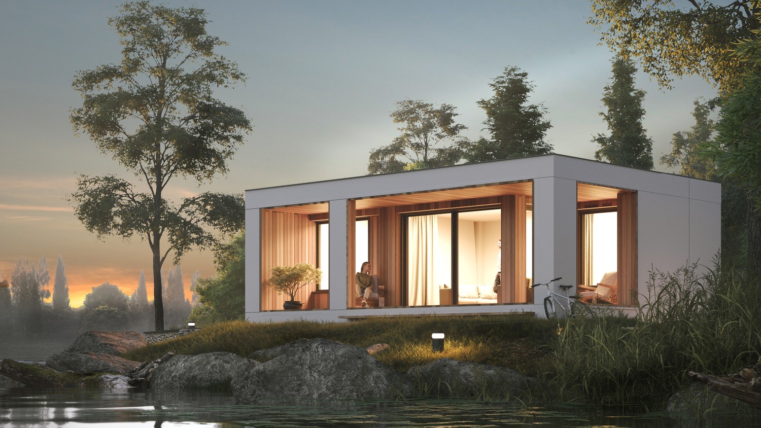Nowoczesny dom modułowy z dużymi oknami, usytuowany nad brzegiem jeziora, z kobietą siedzącą na werandzie, rower oparty o ścianę budynku.
