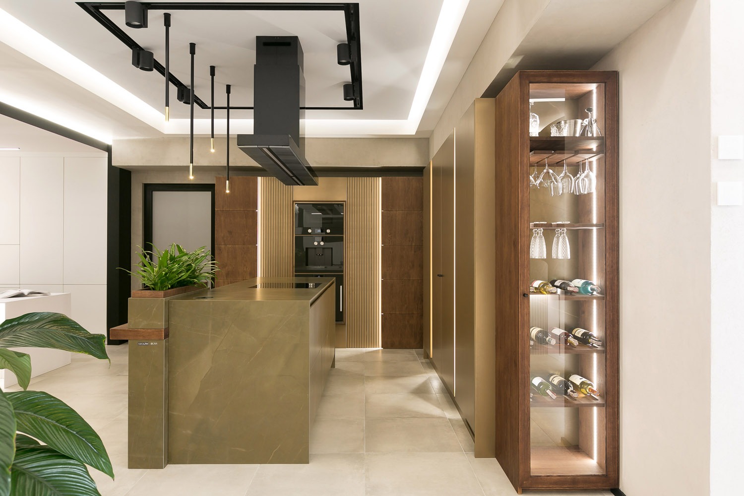 Nowoczesna kuchnia z wyspą o zielonym odcieniu, drewnianymi szafkami z podświetleniem LED, czarnym okapem i przeszkloną witryną z winami i kieliszkami.