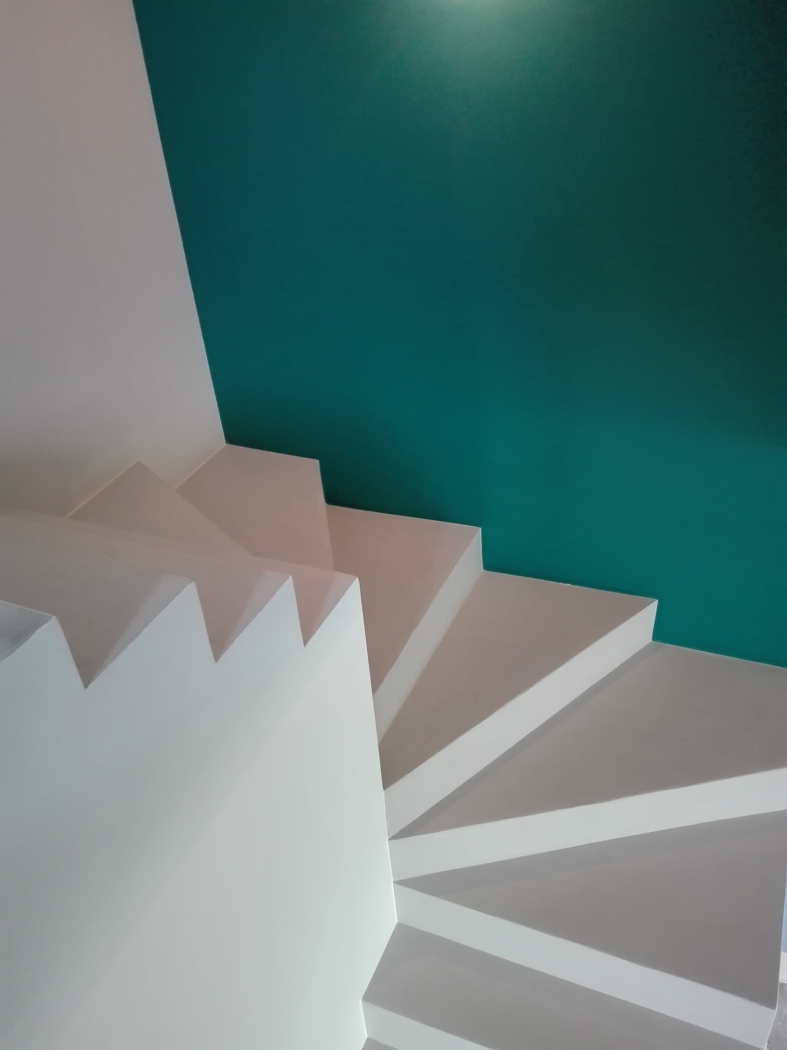 Białe schody z gładko wykończonymi powierzchniami i turkusową ścianą w tle, prezentujące estetyczne wykończenie wnętrza.