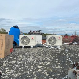 KLIMA STAR - Instalacja dwóch zewnętrznych jednostek klimatyzacji Rotenso Elis na dachu budynku, pracownik w niebieskiej kurtce w trakcie montażu, obok karton po urządzeniu, widoczne przewody i elementy montażowe.