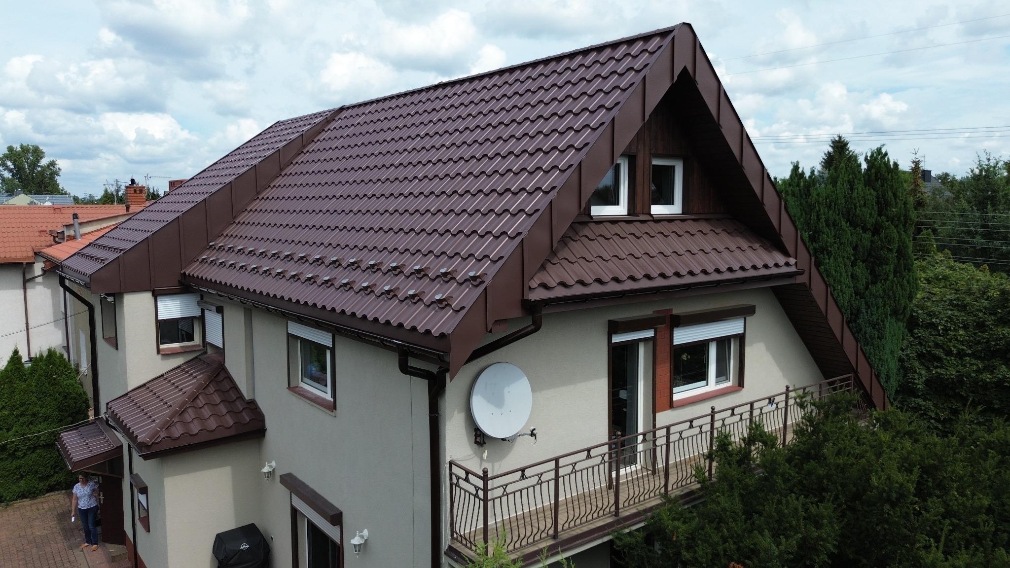 Dom jednorodzinny w Łodzi z nowym, brązowym dachem z blachodachówki, widoczny z góry, z zamontowanymi barierkami przeciwśniegowymi.
