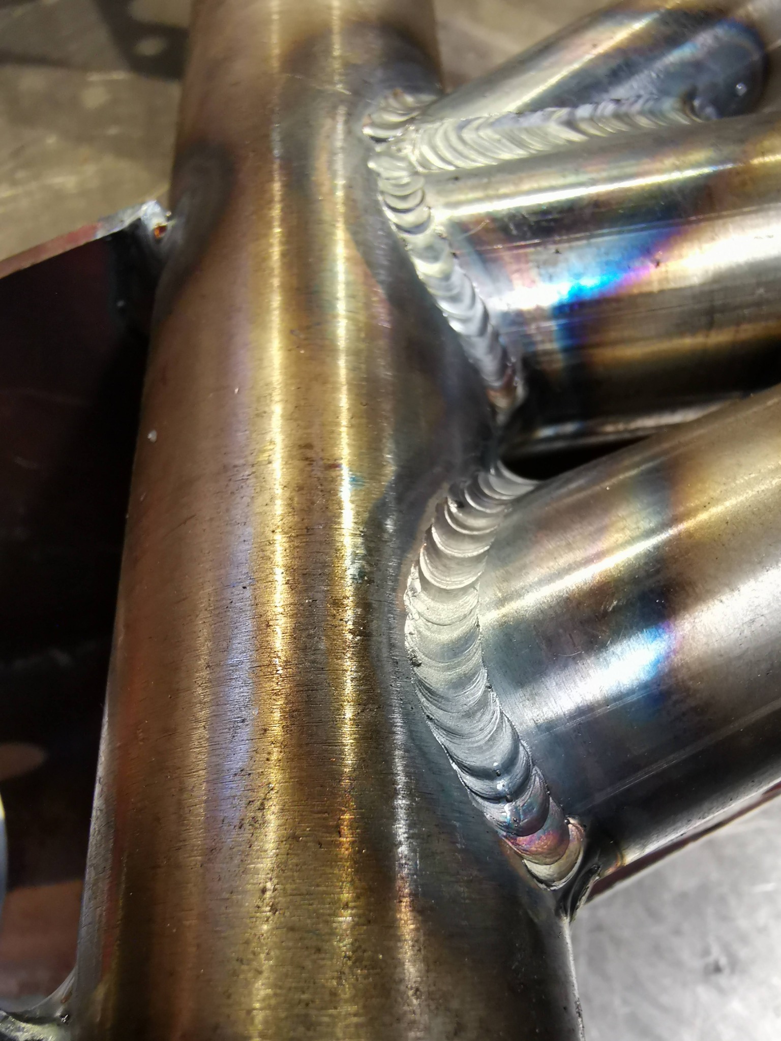 Połączenie spawane rur stalowych, widoczne ślady ciepła i charakterystyczne tęczowe przebarwienia na spoinie