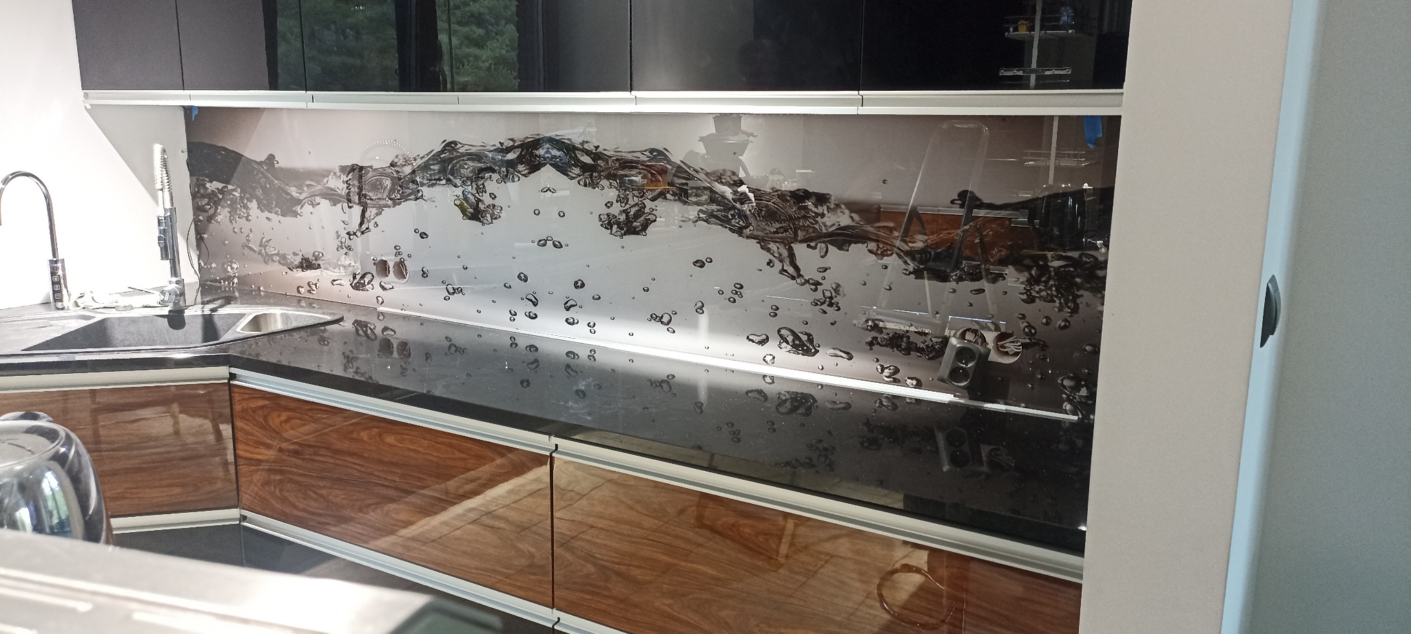 Fronty kuchenne czarny połysk oraz fornir orzech w połysku plus montaż szkła ozdobnego nad blatem.