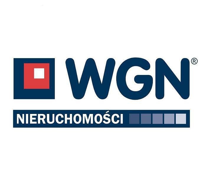 Logo firmy WGN Nieruchomości z kwadratem z czerwonym wypełnieniem i białym kwadratem w środku, obok napis WGN, poniżej napis NIERUCHOMOŚCI i pasek z gradientem koloru niebieskiego.