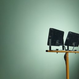 Bud - Świeżo pomalowana ściana w odcieniach zieleni oświetlona dwoma reflektorami LED na żółtym statywie, widoczne niedoskonałości na styku ściany z sufitem.