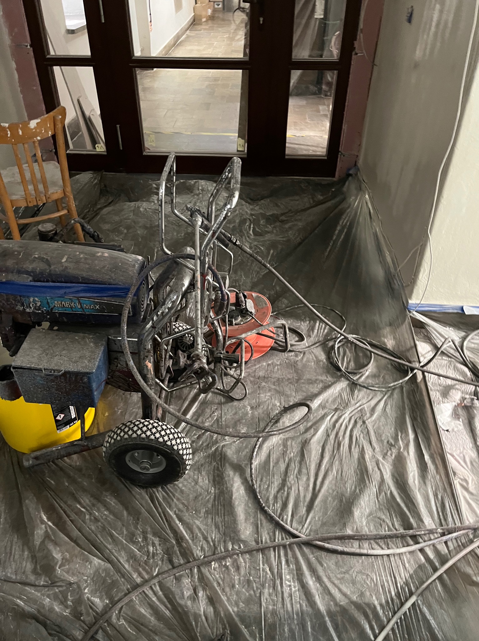 Agregat malarski Mark V Max na folii ochronnej podczas prac wewnątrz budynku, widoczny fragment ściany i drzwi.