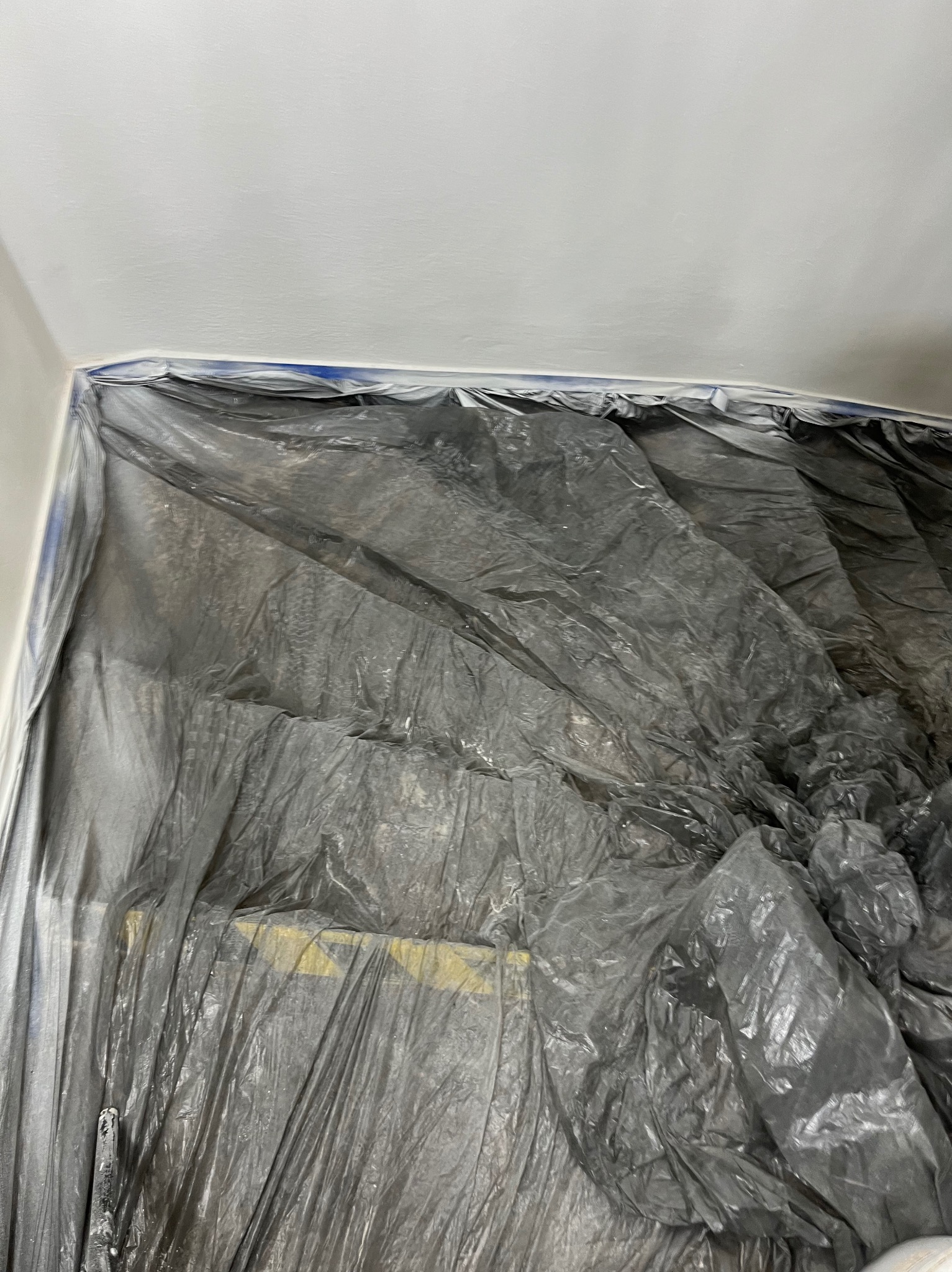 Pokój zabezpieczony folią malarską przed zabrudzeniem, widoczna taśma malarska przy suficie.