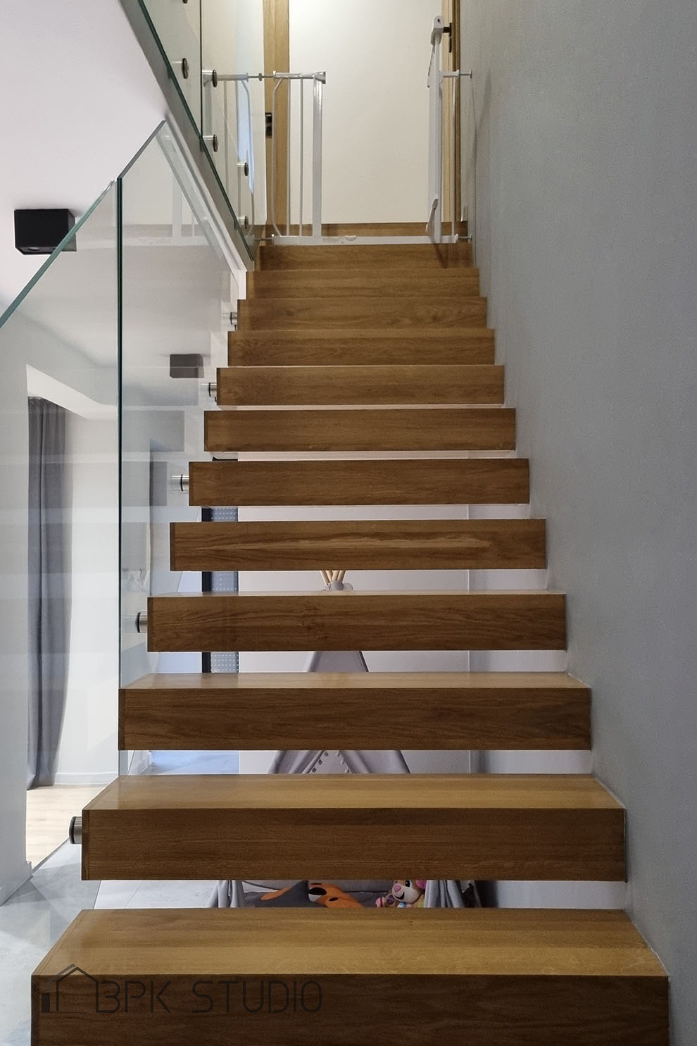 Nowoczesne schody drewniane z balustradą ze szkła hartowanego, zabezpieczenie dla dzieci na górze, widok z dołu.