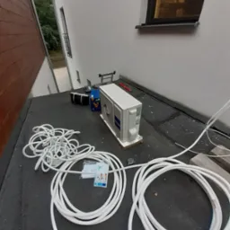 Przygotowanie do montażu klimatyzatora Haier na dachu budynku, widoczne zwinięte kable, skrzynka narzędziowa i instrukcja obsługi.