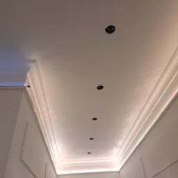 Biały sufit z listwami dekoracyjnymi i przygotowanymi otworami na oświetlenie punktowe, widoczne także panele ścienne.