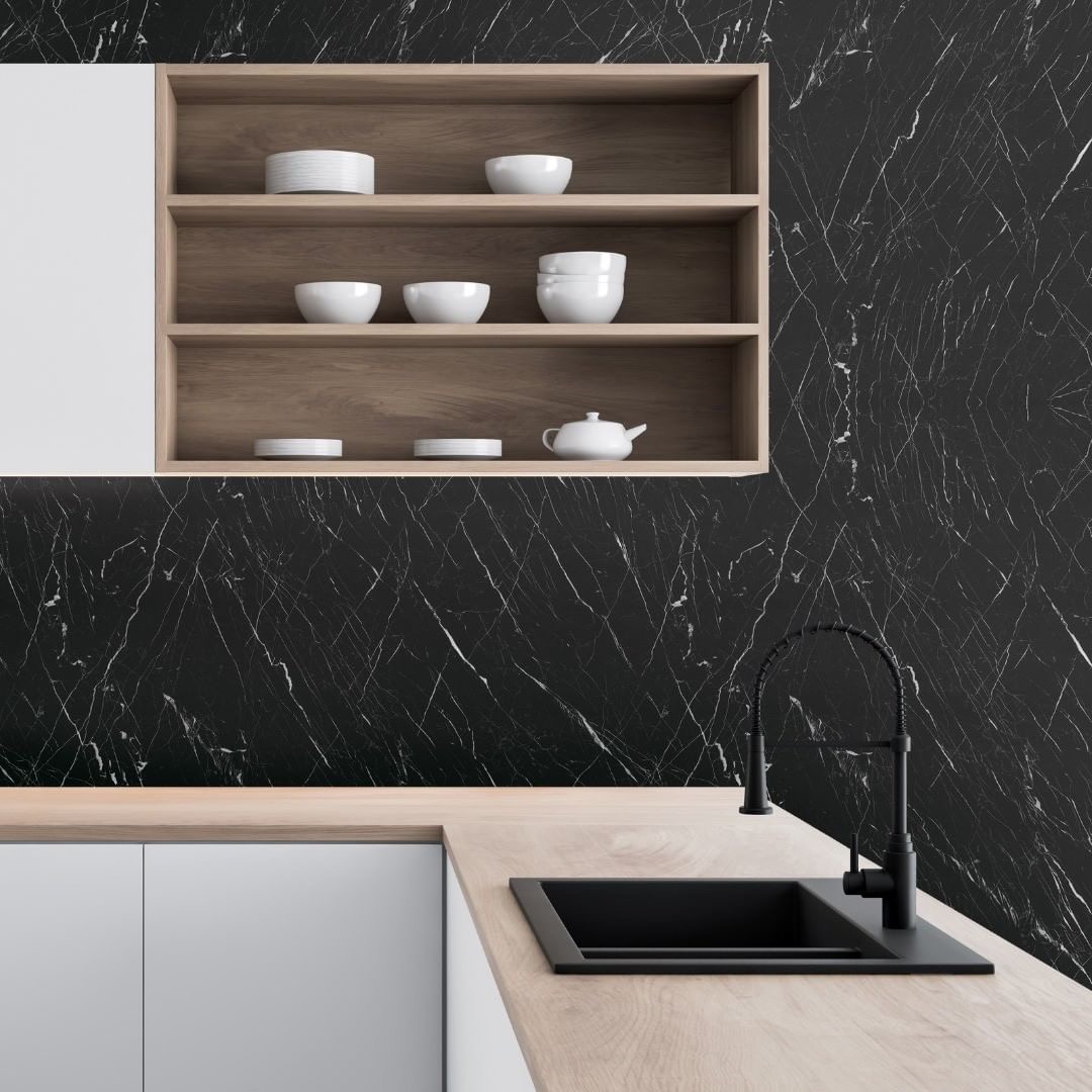 Wnętrze kuchni z czarnym marmurowym backsplashiem, drewnianymi półkami z białymi naczyniami i czarnym zlewem z baterią.