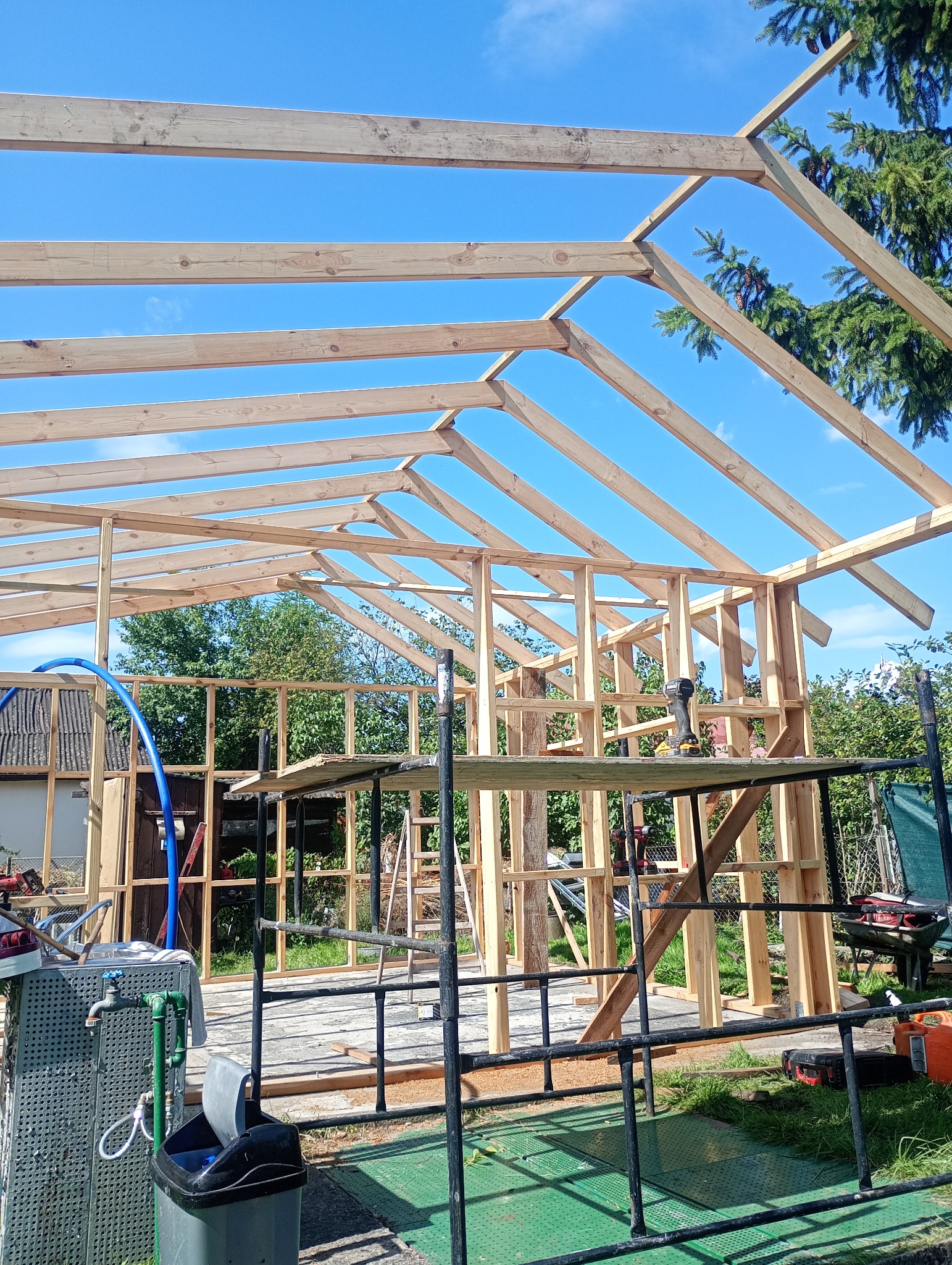 Konstrukcja drewniana domu w trakcie budowy w Szczecinie, widok z dołu na szkielet budynku i niebo. Widoczne narzędzia i rusztowania.