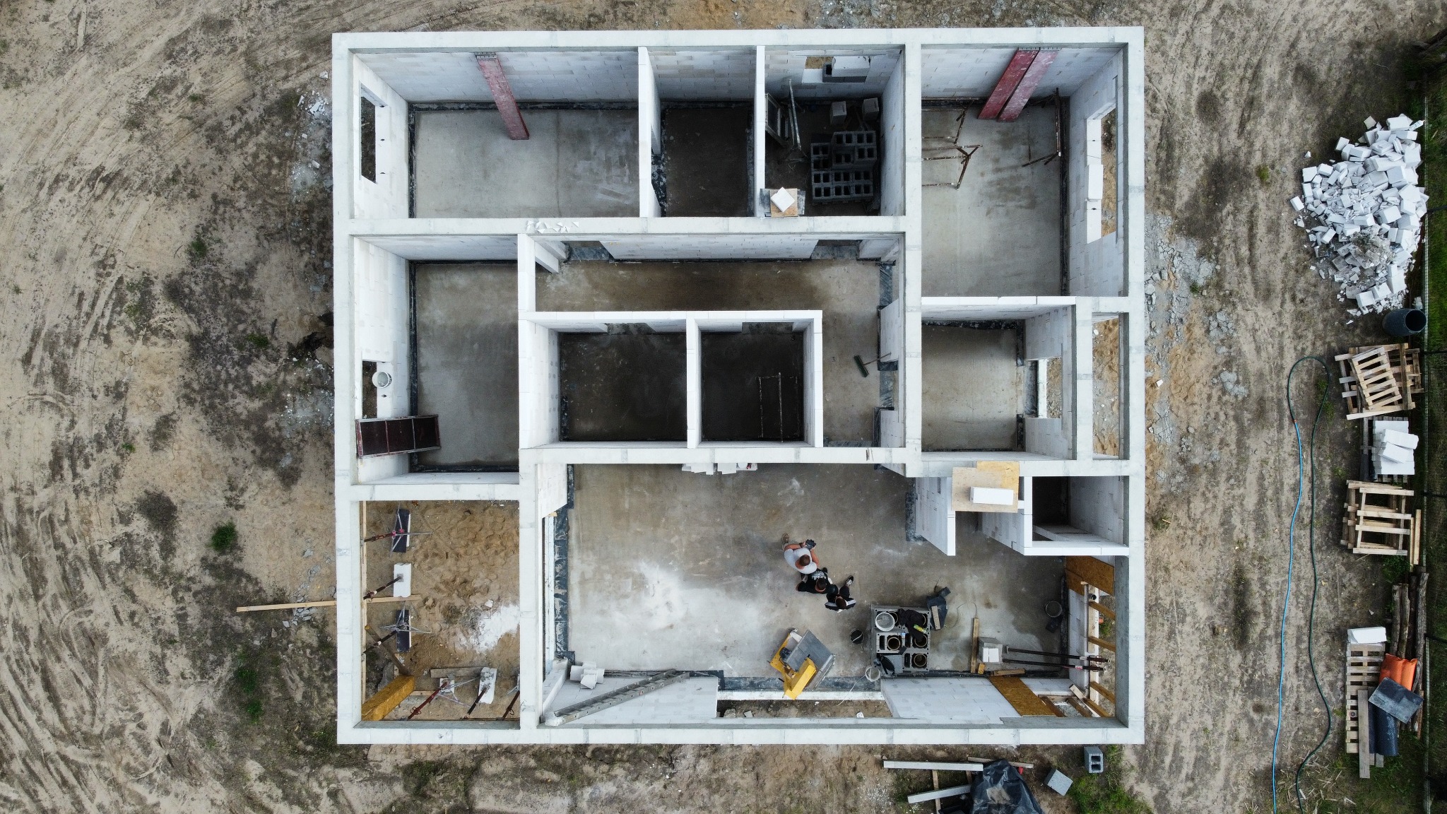 Zdjęcie z lotu ptaka przedstawia budynek w stanie surowym otwartym w Boleszkowicach, z widocznymi ścianami z betonu komórkowego, narzędziami i dwoma osobami wewnątrz.
