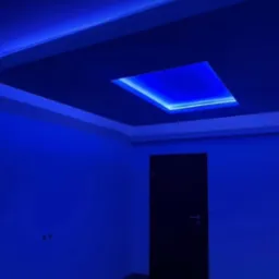 Pokój z podwieszanym sufitem i oświetleniem LED w kolorze niebieskim, ciemne drzwi w tle.