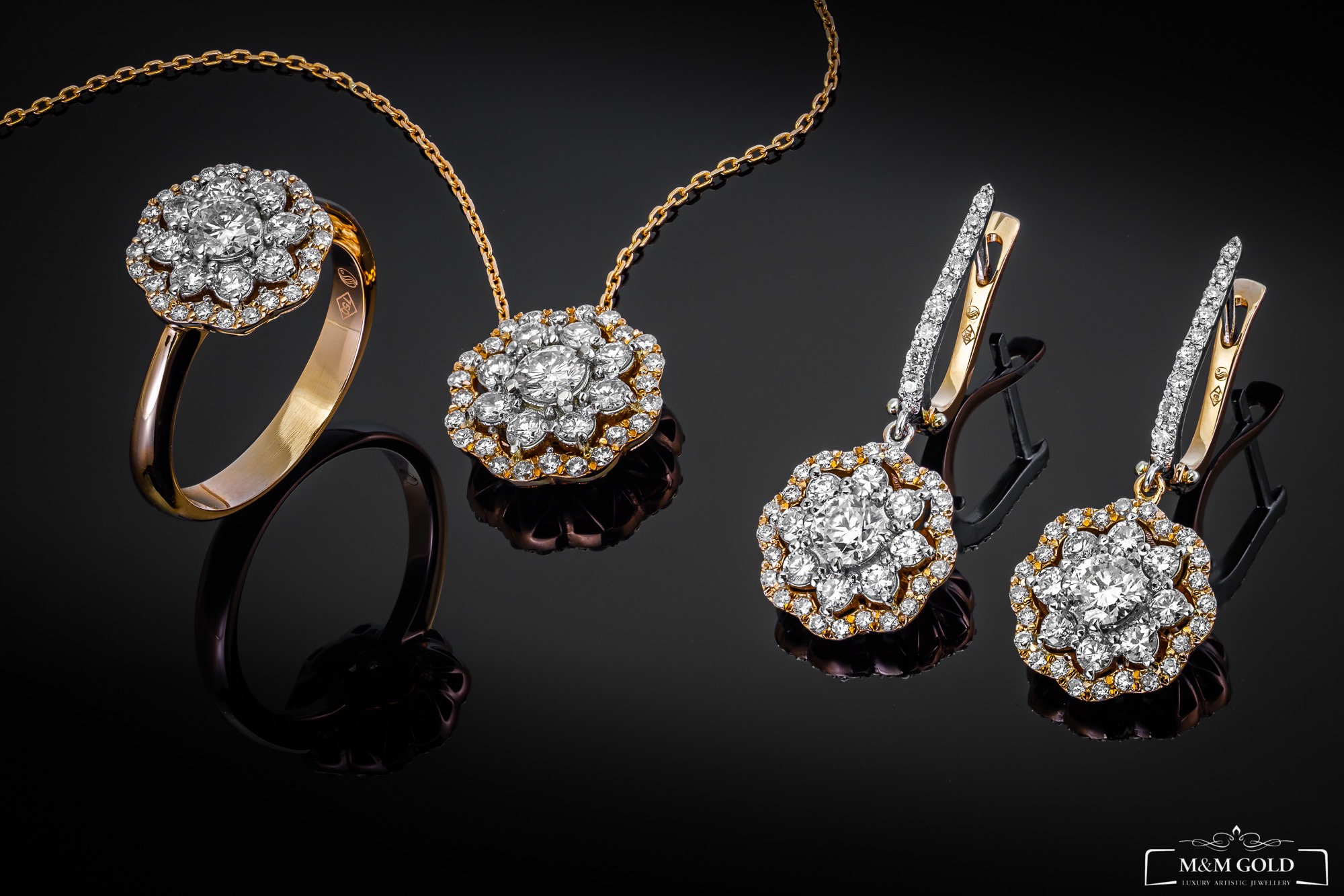 Zestaw złotej biżuterii z diamentami: pierścionek, naszyjnik i kolczyki na błyszczącym czarnym tle, z widocznym logo jubilera w prawym dolnym rogu.
