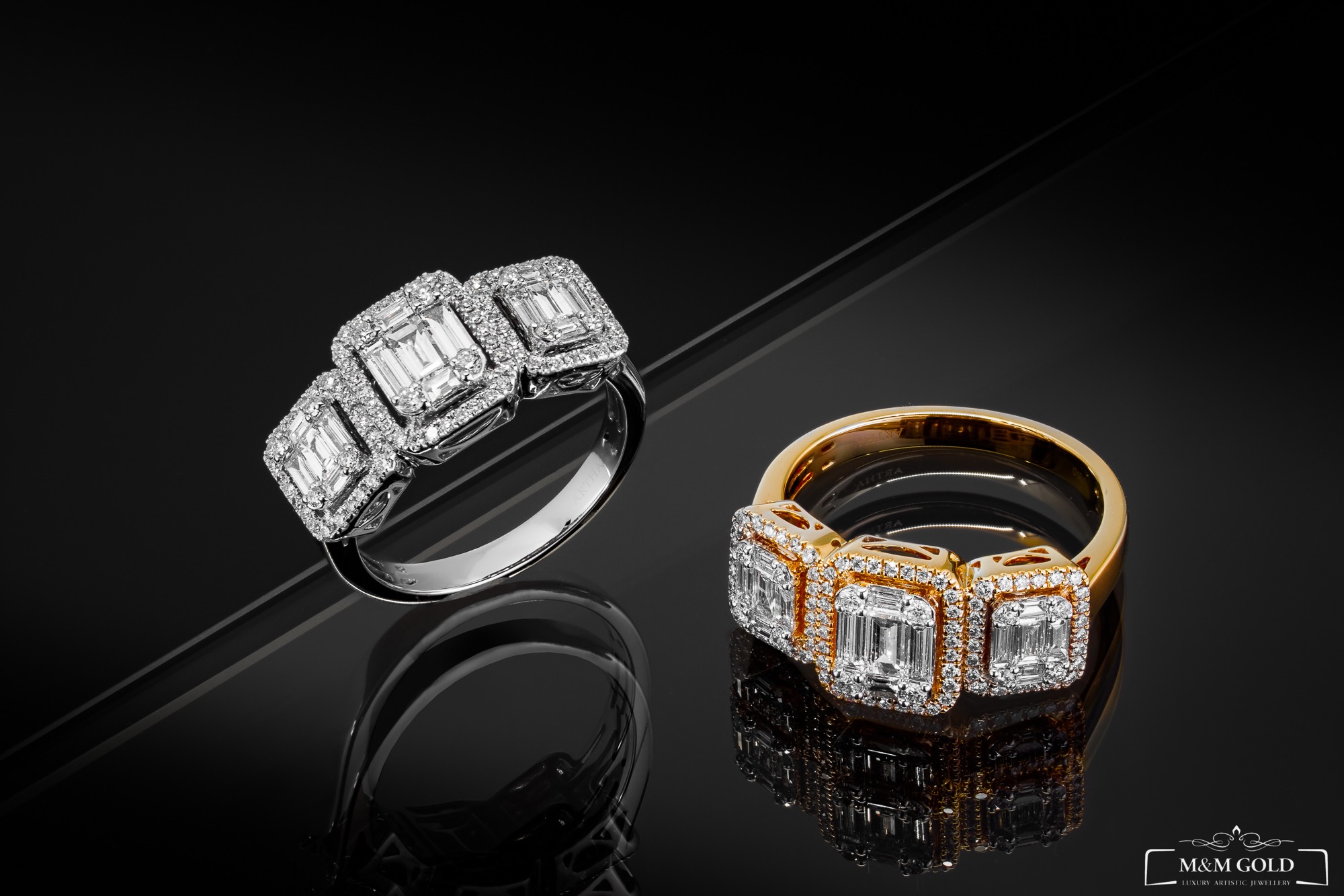 Dwa pierścionki z brylantami: jeden srebrny, drugi złoty, oba z trzema kwadratowymi brylantami otoczonymi mniejszymi kamieniami, leżące na czarnej, błyszczącej powierzchni odbijającej ich kształty.