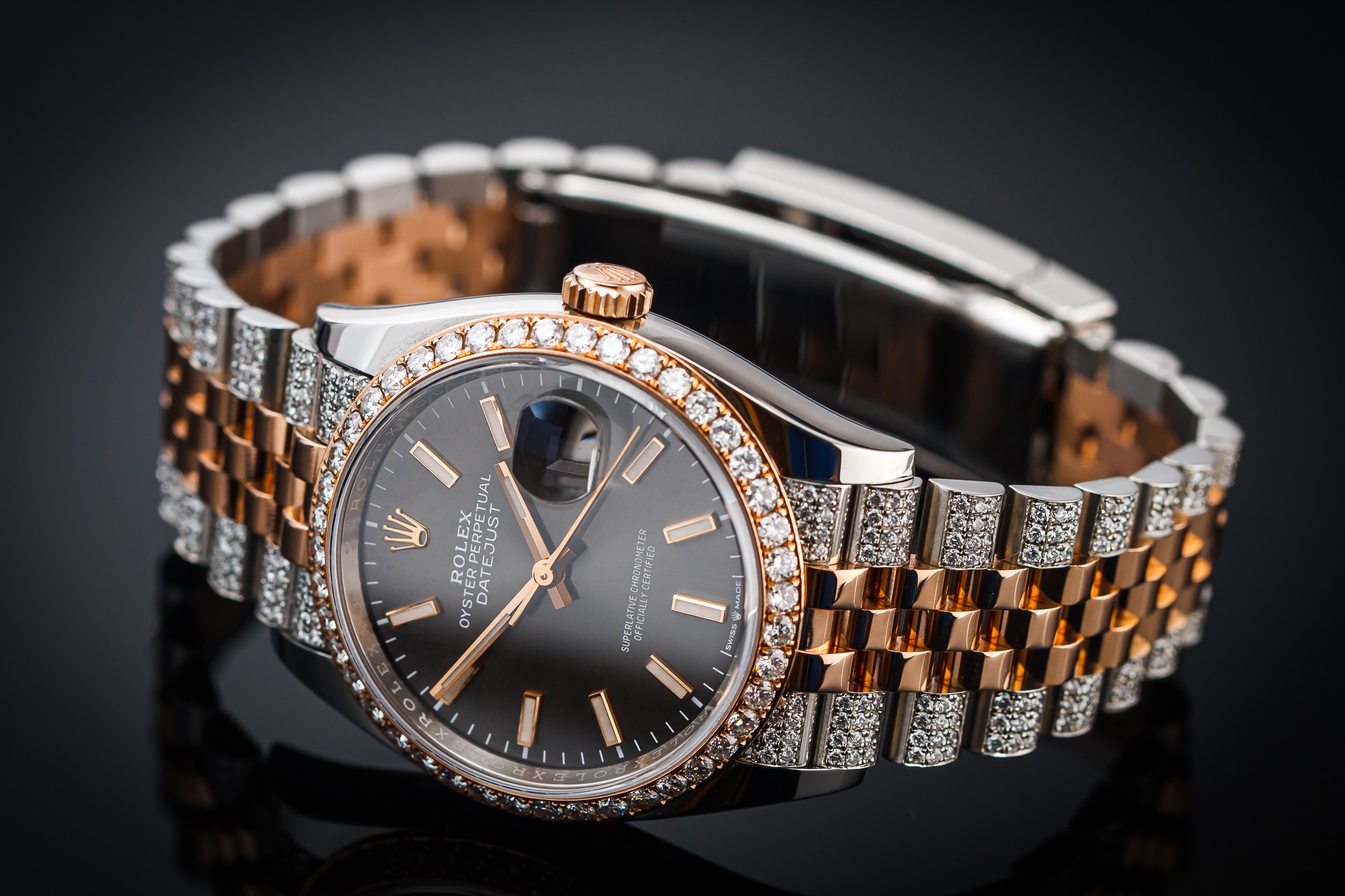 Zegarek naręczny Rolex Datejust z bransoletą jubilerską, wysadzany diamentami na bezelu i ogniwach bransolety, na czarnym, błyszczącym tle.