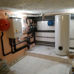 Kotłownia z zainstalowanym zbiornikiem ciepłej wody, kotłem gazowym i rozbudowaną instalacją hydrauliczną z czarnymi rurami, widoczne elementy montażowe i narzędzia.