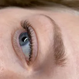 Detaliczny widok oka z przedłużonymi, gęstymi rzęsami, widoczny delikatny blask w źrenicy i naturalny kształt brwi.