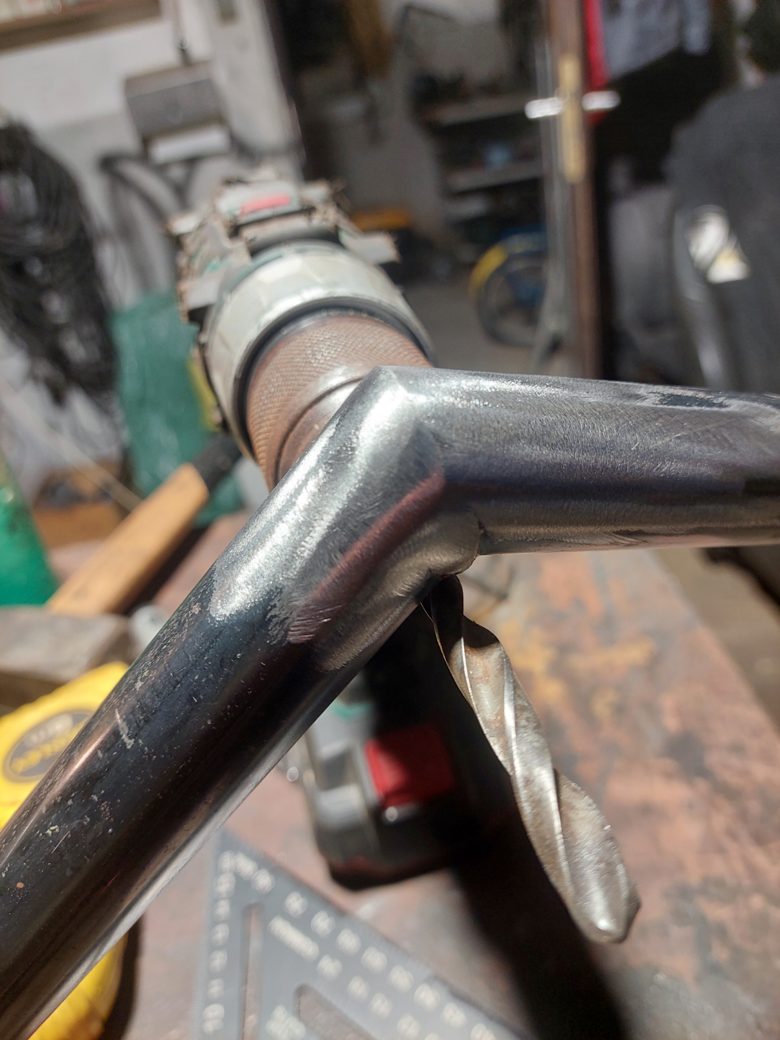 Proces wiercenia otworu w metalowym profilu za pomocą wiertarki; widoczne ślady obróbki i wióry.