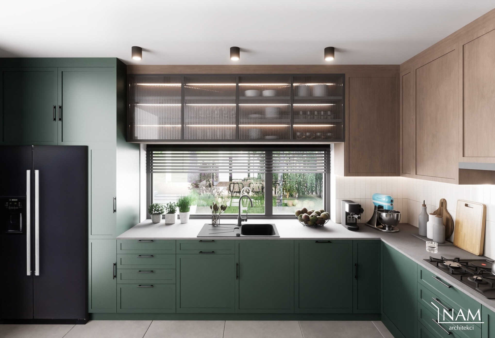 Nowoczesna kuchnia w odcieniach zieleni i drewna, z czarną lodówką i oknem z widokiem na ogród. Górne szafki z ryflowanymi szklanymi frontami podświetlone LED, na blacie ekspres do kawy i mikser.