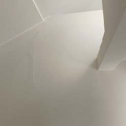 Perfect Wall - Świeżo pomalowane na kremowo ściany i sufit z listwami wykończeniowymi, widoczny fragment wiszącego kabla.