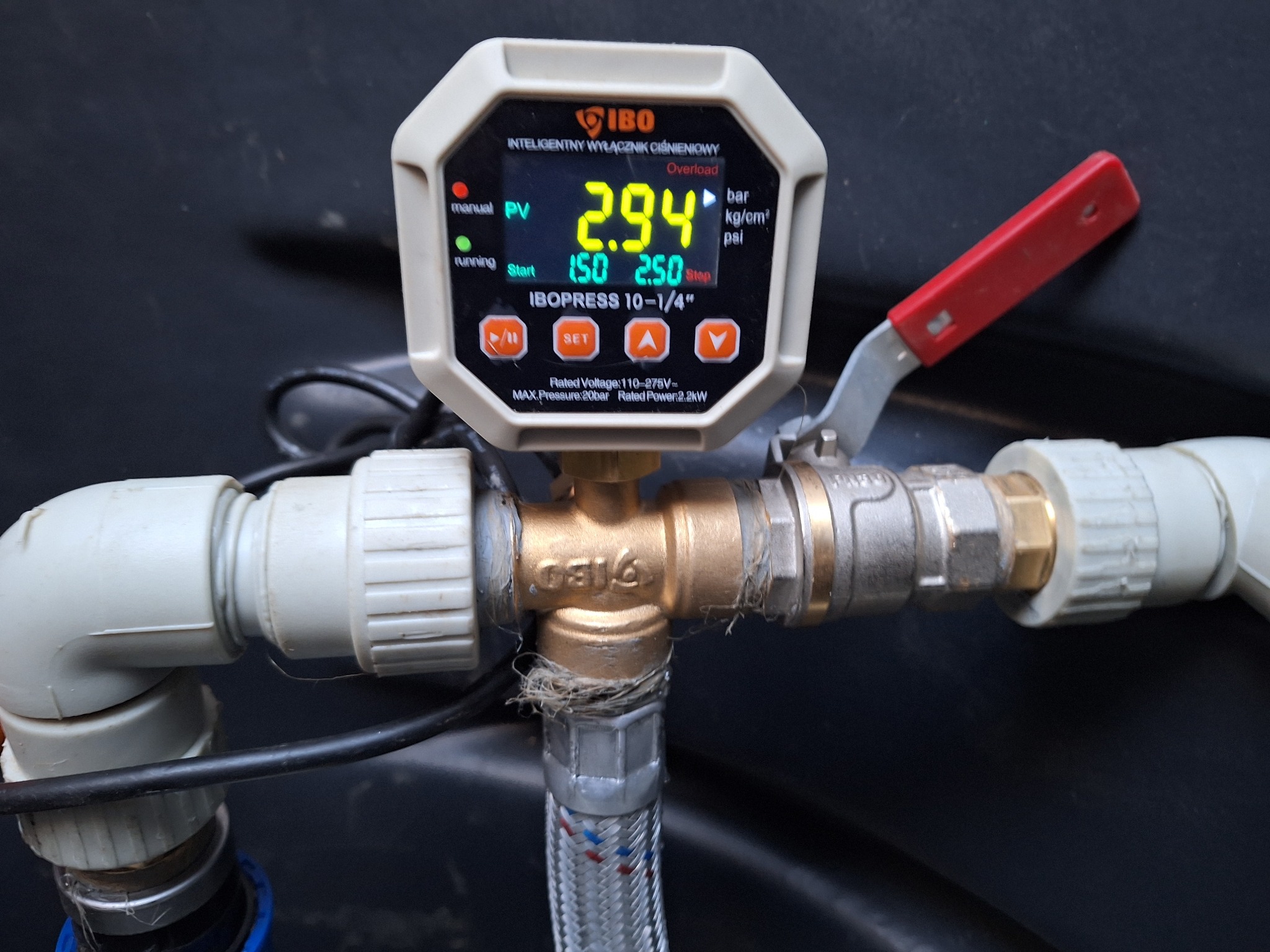 Manometr IBOpress 10-1/4 cala podłączony do instalacji wodnej z zaworem, wskazujący ciśnienie 2.94 bar, z widocznymi elementami złącznymi i przewodami z tworzywa sztucznego.