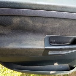 MARTOM Martyna LANGER - Wnętrze drzwi samochodu z widocznymi zabrudzeniami na tapicerce i plastikowych elementach, wymagające czyszczenia.
