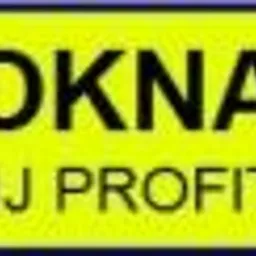 Żółta tabliczka z czarnym napisem 'OKNA JJ PROFIT' w zaokrąglonym prostokącie. Widoczne drobne niedoskonałości druku na powierzchni.