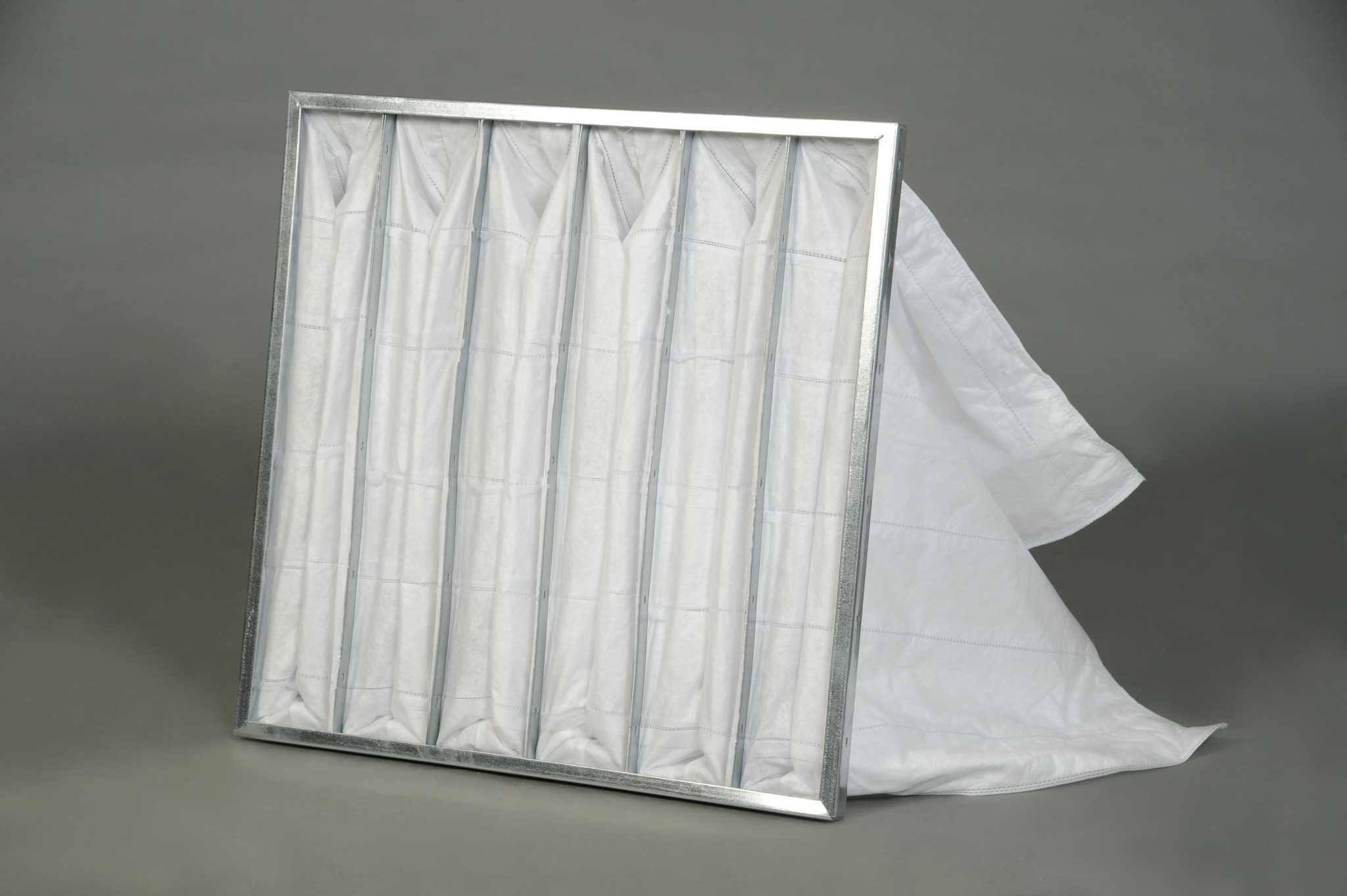 Filtr kieszeniowy z metalową ramą, widoczne szwy na białym materiale filtracyjnym, prezentowany na szarym tle.