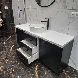 Remigiusz Aksamit - Nowoczesna szafka łazienkowa na wymiar w czerni i bieli, z okrągłym lustrem i otwartymi szufladami, na tle marmurowych płytek. Eleganckie wykończenie.