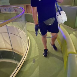 Z POŁYSKIEM Bartłomiej Zienkiewicz - Pracownik w Łukowie dezynfekuje podłogę w centrum handlowym, używając opryskiwacza. Widoczna część balustrady i oznaczenia sklepów w tle.