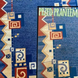 Dywan w geometryczne wzory, podzielony na dwie części: lewa strona „po praniu”, prawa „przed praniem”, ukazująca różnicę w kolorze i czystości.