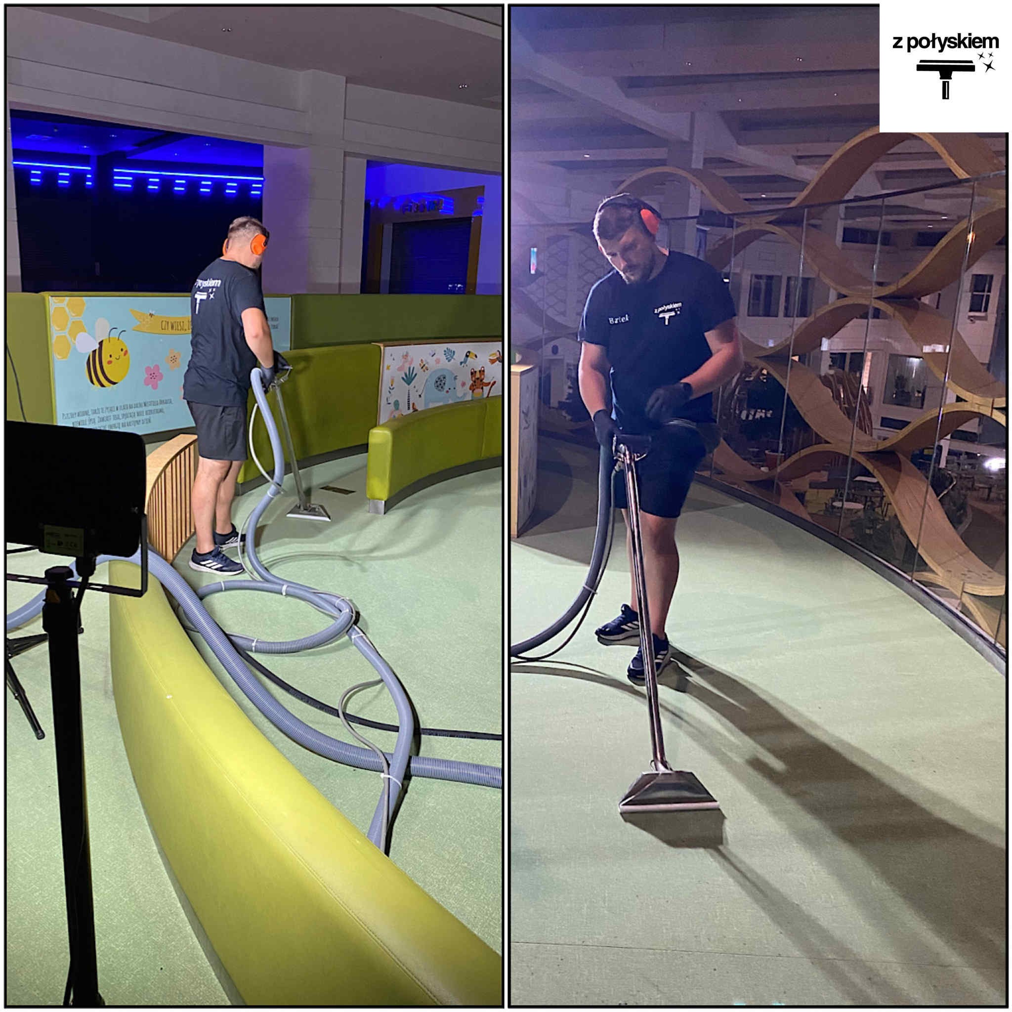 Pracownik w słuchawkach i czarnym uniformie czyści wykładzinę w budynku użyteczności publicznej za pomocą profesjonalnego odkurzacza piorącego. Widoczne elementy wystroju.