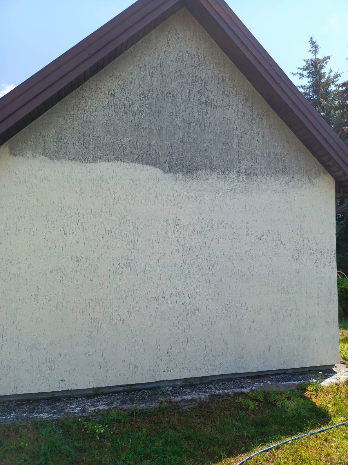 Fragment ściany budynku z widoczną różnicą w czystości elewacji, prawdopodobnie po czyszczeniu. Dolna część jaśniejsza, górna ciemniejsza.