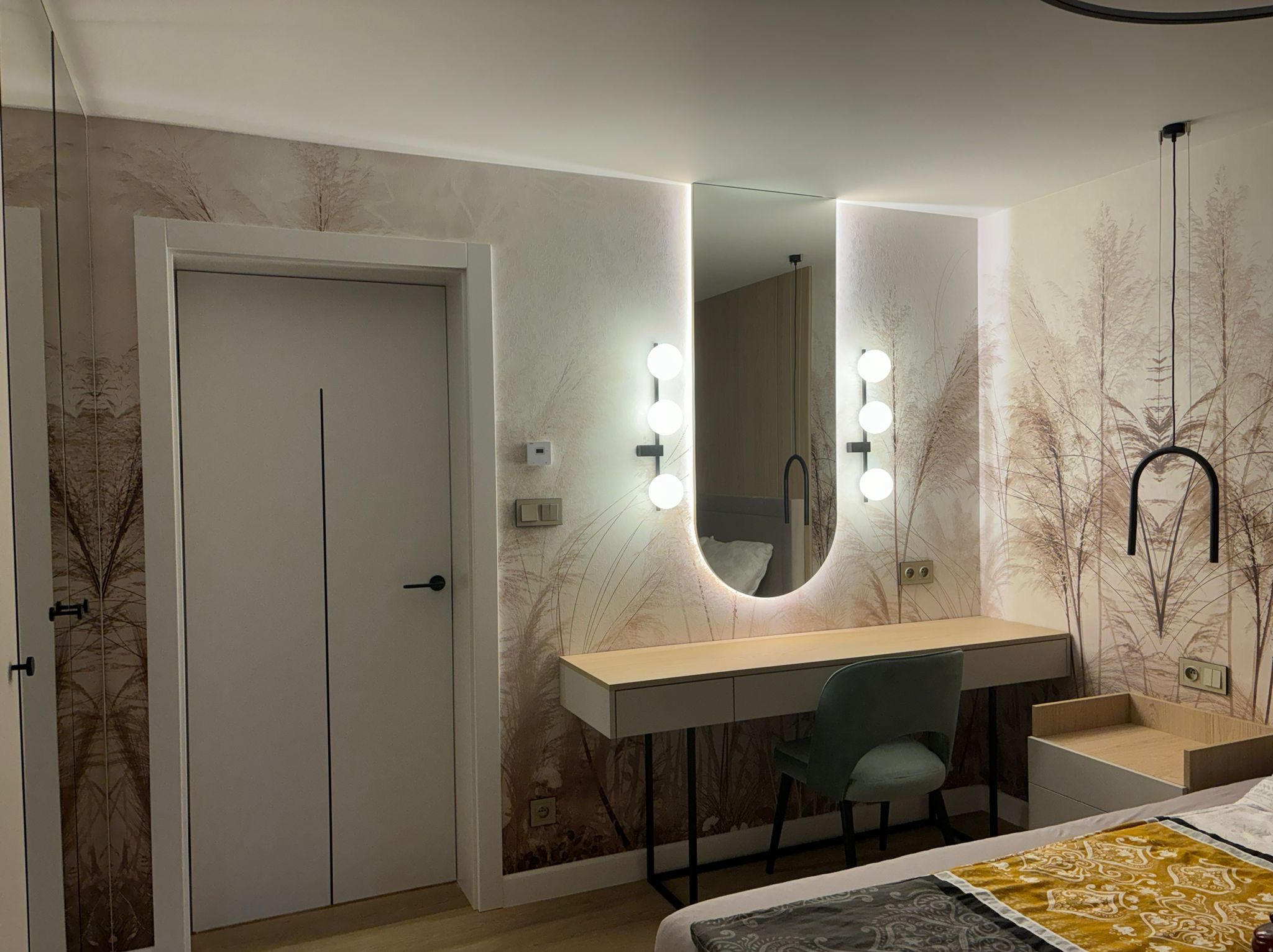 Nowoczesna sypialnia w Białej Podlaskiej po remoncie, z toaletką z podświetlanym lustrem, tapetą w motywy roślinne i drzwiami w kolorze złamanej bieli.