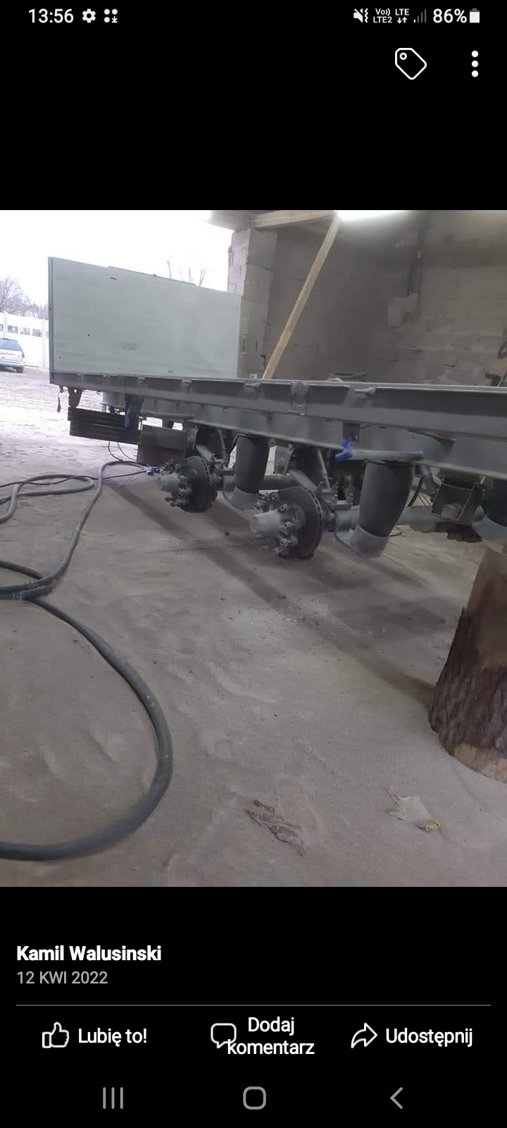 Podwozie ciężarówki po renowacji, pomalowane na szaro, widoczne koła i zawieszenie pneumatyczne w hali warsztatowej, z przewodem na podłodze.