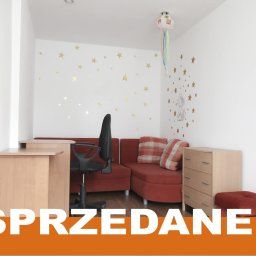 Biuro Nieruchomości Dariusz Wika - Pokój z biurkiem, krzesłem i sofą, udekorowany naklejkami gwiazd. Na zdjęciu widoczny napis 'Sprzedane' i 'Gratulacje'.