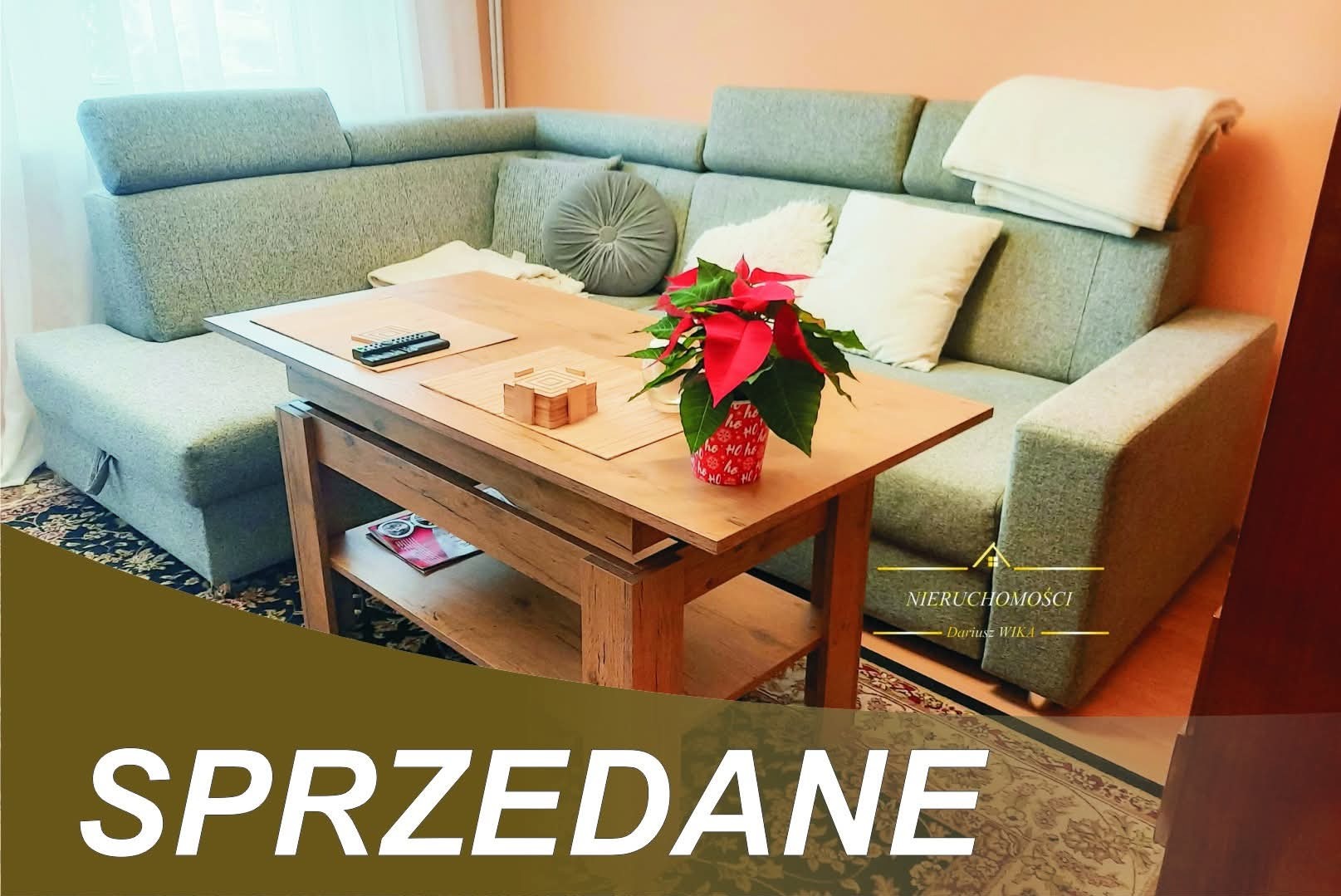 Jasny salon z narożnikiem, drewnianym stolikiem kawowym i świąteczną dekoracją. Na pierwszym planie napis 'SPRZEDANE'.
