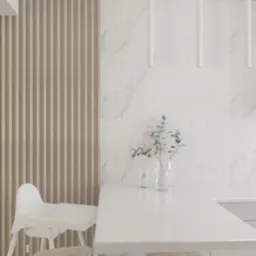 Jasna kuchnia w minimalistycznym stylu z marmurową ścianą, drewnianymi lamelami i białym blatem, na którym stoją świeca i gałązka eukaliptusa w szklanym wazonie, widoczne krzesełko do karmienia...