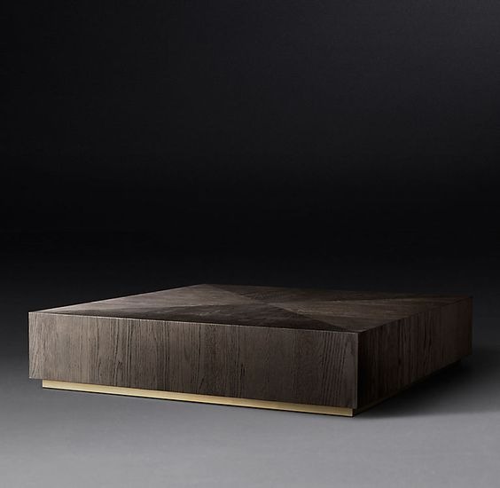 Kwadratowy stolik kawowy z ciemnego drewna z wyraźnym usłojeniem, osadzony na niskiej, złotej podstawie, na neutralnym tle.
