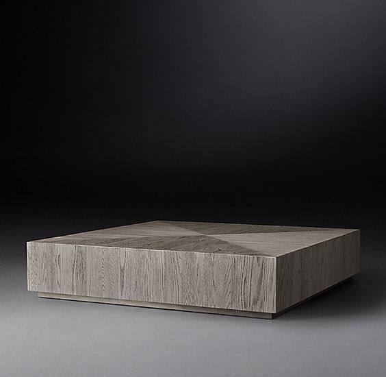 Kwadratowy stolik kawowy z drewna o jasnoszarym wybarwieniu, z widocznym usłojeniem i geometrycznym wzorem na blacie, umieszczony na niskiej podstawie.