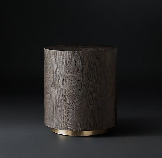 Walec z ciemnego drewna z wyraźnym usłojeniem, osadzony na niskiej, złotej podstawie, na ciemnym tle.