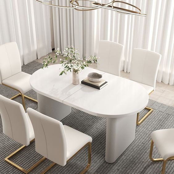 Elegancki, rozkładany stół z białym blatem i krzesłami na złotych nogach w jasnym wnętrzu w Krakowie, ozdobiony wazonem z kwiatami i dekoracyjną misą.