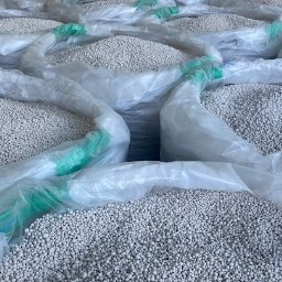 P.P.H.U Prohaus - Foliowe worki wypełnione białymi granulkami, prawdopodobnie nawozami, ułożone jeden obok drugiego.