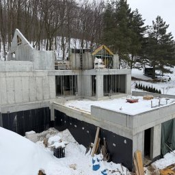 Petropol Sp. z O.O. - Surowy stan domu z betonu w zimowej scenerii. Widoczne szalunki, zbrojenia i izolacja fundamentów. Częściowo zadaszona konstrukcja w Redzie.