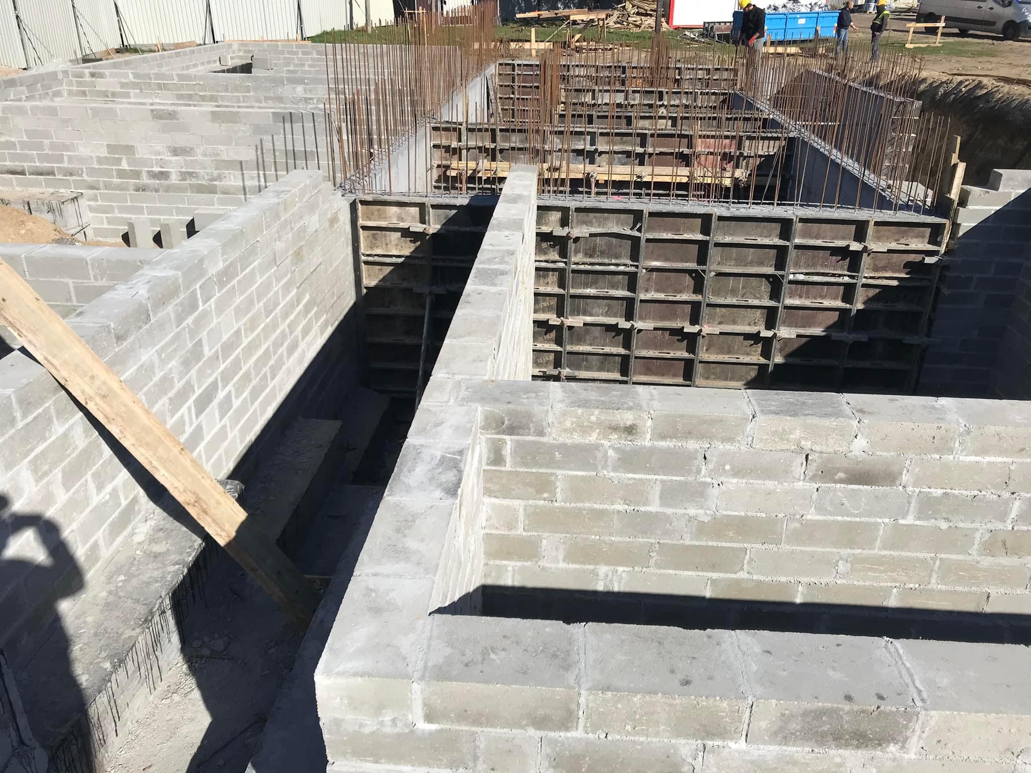 Wykopany fundament z szalunkiem i częściowo wymurowanymi ścianami z bloczków betonowych.