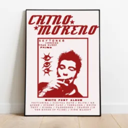 Plakat albumu White Pony zespołu Deftones z wizerunkiem Chino Moreno, utrzymany w czerwonej kolorystyce, prezentowany w ramce na tle ściany i podłogi w Zielonej Górze.