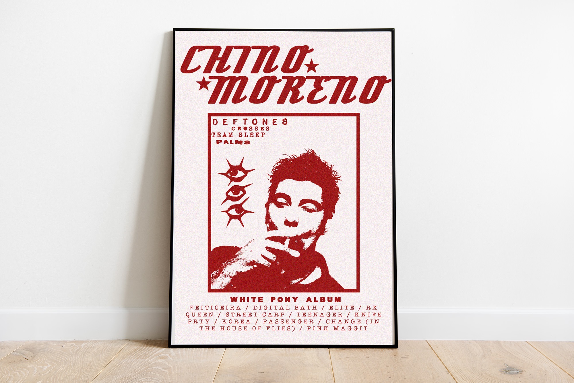 Plakat albumu White Pony zespołu Deftones z wizerunkiem Chino Moreno, utrzymany w czerwonej kolorystyce, prezentowany w ramce na tle ściany i podłogi w Zielonej Górze.